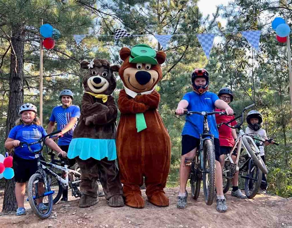 Family enjoying bikes and activities with Yogi Bear and Cindy Bear at Asheboro Jellystone Park in North Carolina