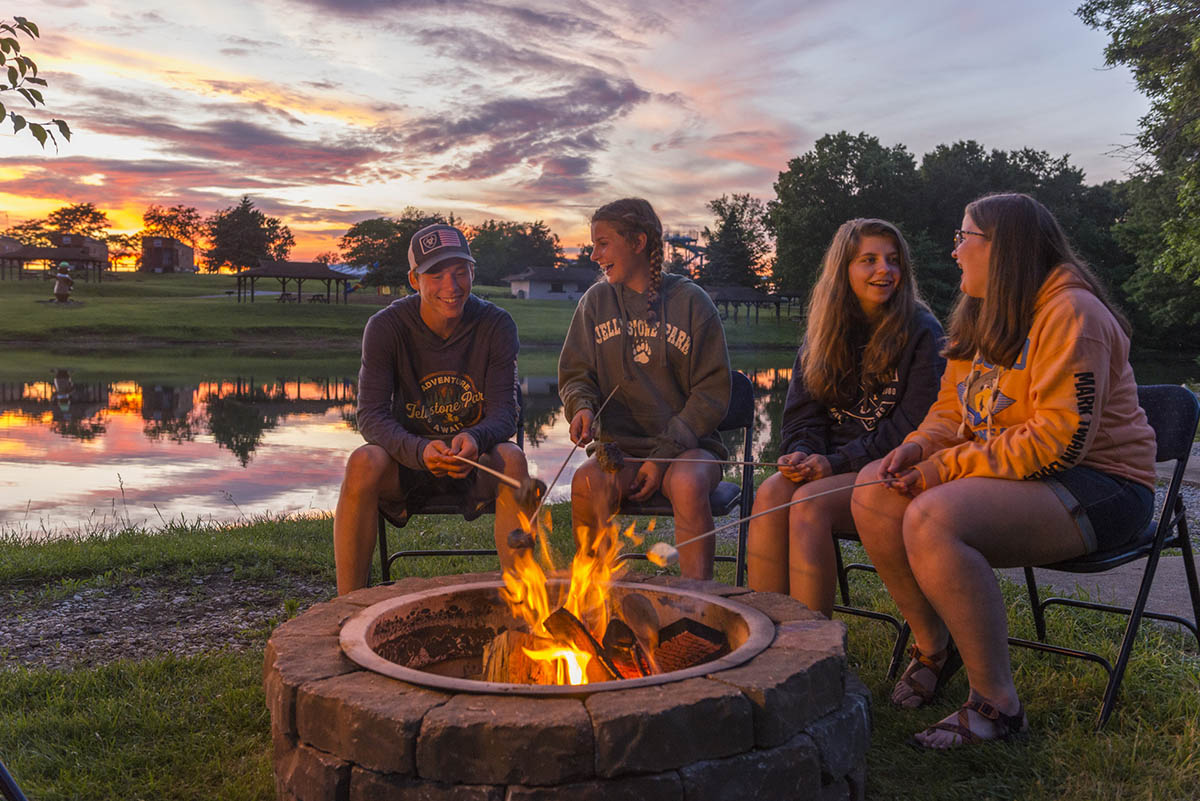 Family Campfire at Sunset | Asheboro Jellystone Park™ Family enjoying a campfire at sunset during a camping vacation at Yogi Bear's Jellystone Park™ in Asheboro, North Carolina