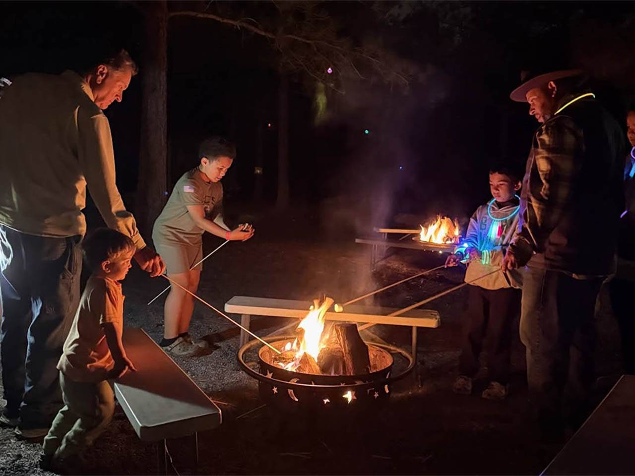 Family gathered around a campfire at Asheboro Jellystone Park